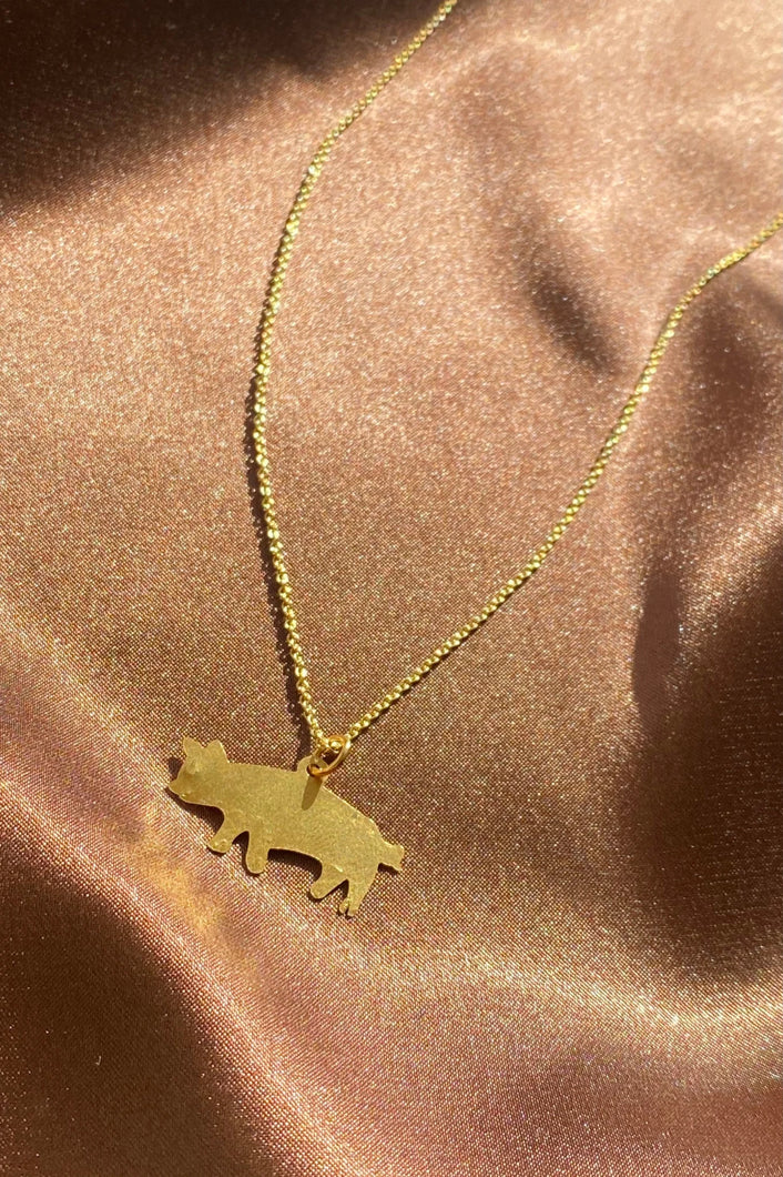 dainty gold pig pendant on a thin chain